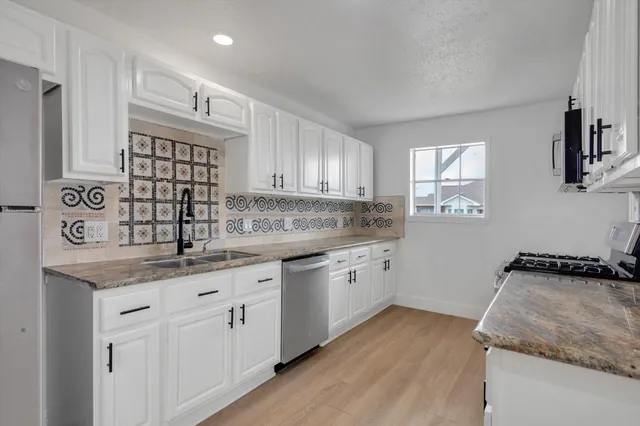 a kitchen with granite countertop cabinets stainless steel appliances a sink and a window