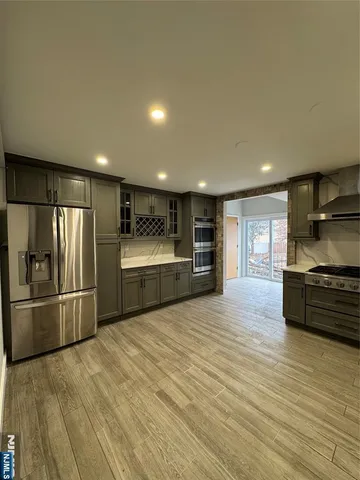 a large kitchen with stainless steel appliances granite countertop a refrigerator and a stove top oven