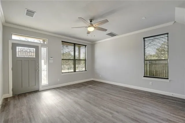 a view of an empty room with wooden floor and a window