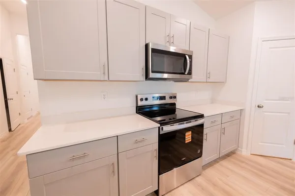 a view of kitchen with stainless steel appliances granite countertop white cabinets and a refrigerator