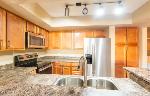 a kitchen with stainless steel appliances granite countertop a refrigerator a stove and a sink with wooden floors