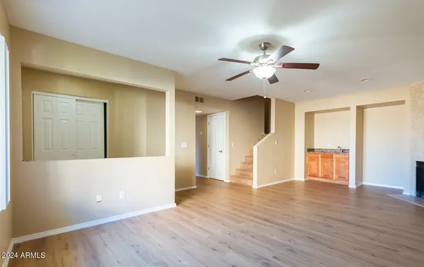a view of an empty room with wooden floor and a ceiling fan