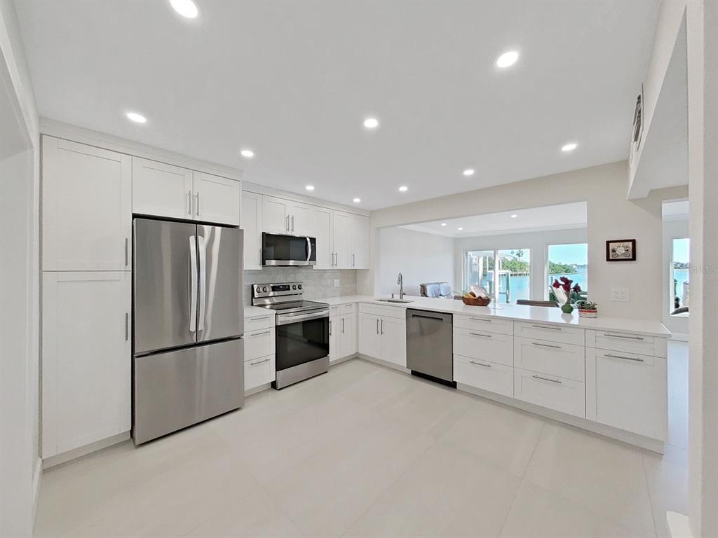 825 East Gulf Boulevard, Unit 110 Indian Rocks Beach, FL 33785 - Photo 13 of 75 a kitchen with white cabinets and stainless steel appliances