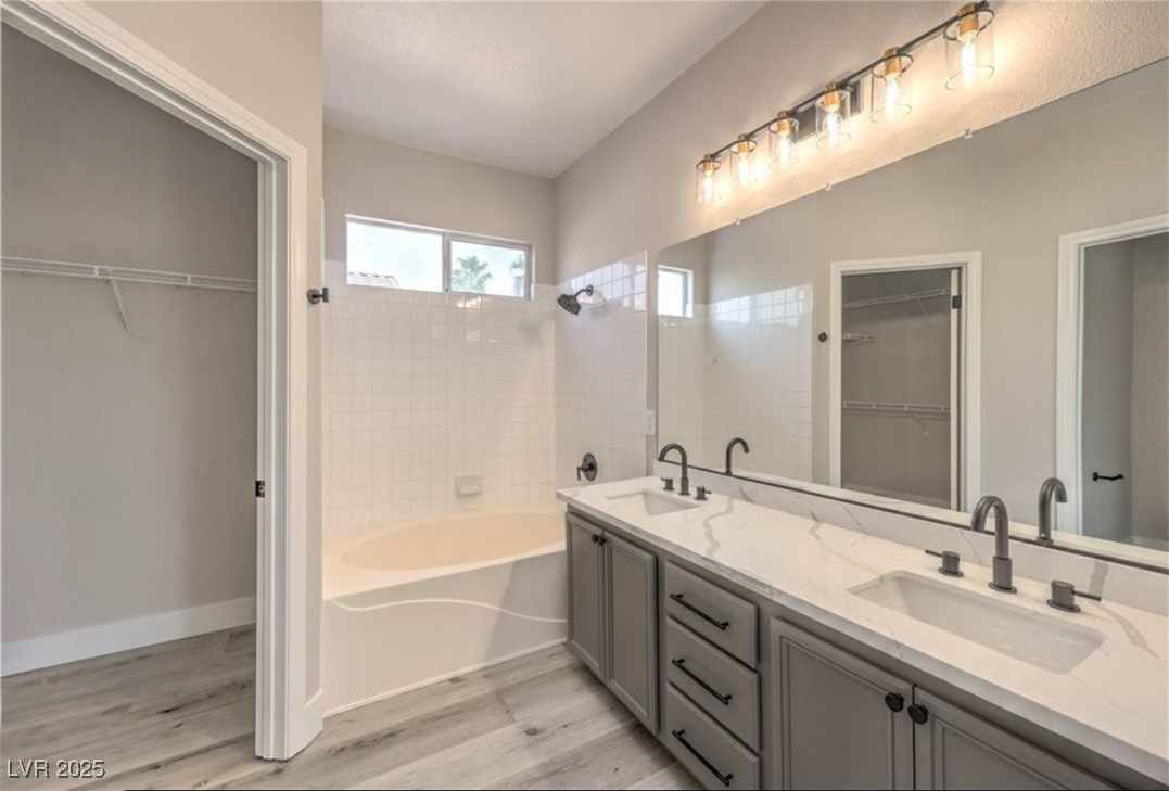 979 Park Bridge Avenue Las Vegas, NV 89123 - Photo 26 of 57 Full bathroom featuring double vanity, a spacious closet, light wood finished floors, and shower / bath combination