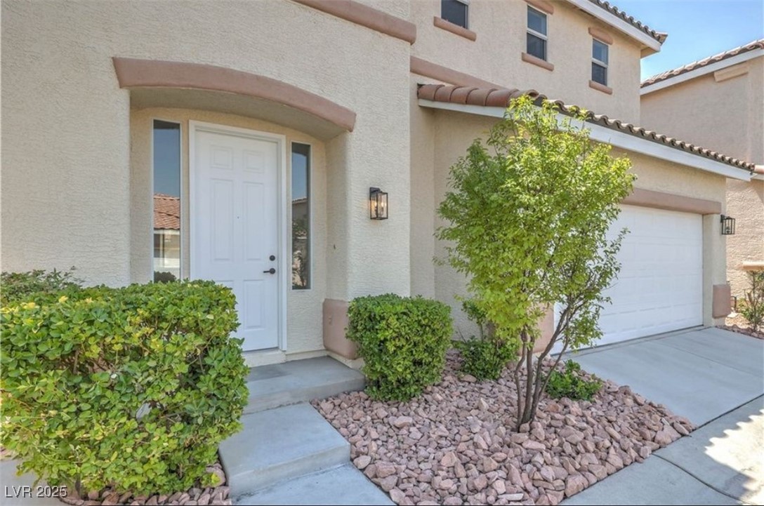 979 Park Bridge Avenue Las Vegas, NV 89123 - Photo 4 of 57 Doorway to property with concrete driveway, stucco siding, and a tile roof