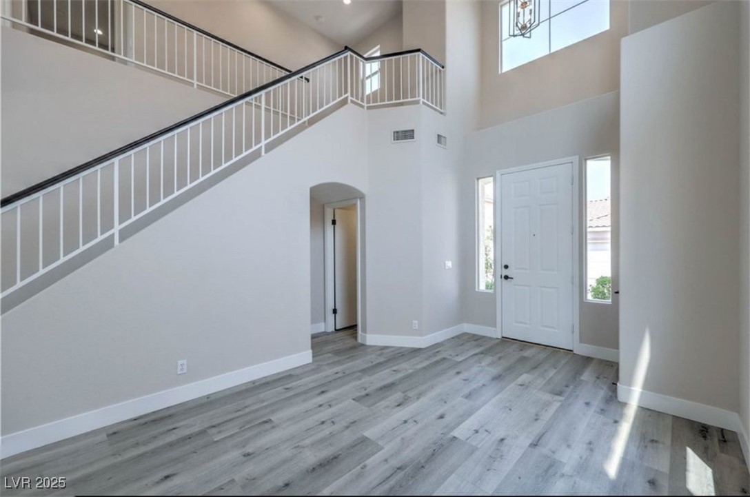 979 Park Bridge Avenue Las Vegas, NV 89123 - Photo 5 of 57 Entryway featuring arched walkways, a towering ceiling, light wood-style floors, and stairs