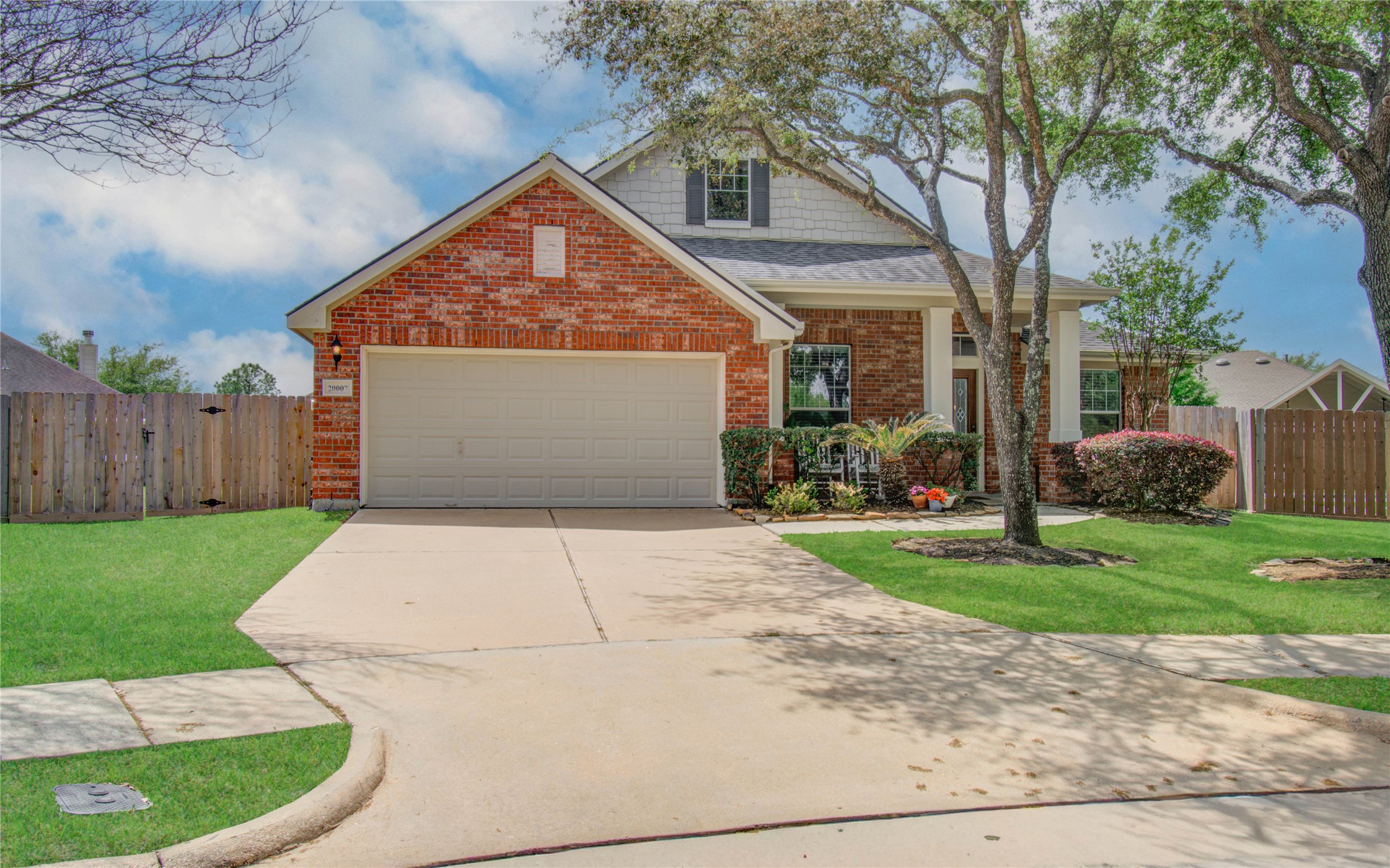20007 Alcea Court Spring, TX 77379 - Photo 3 of 36 Charming brick home with a two-car garage and a well-maintained front yard. Features a wide driveway, welcoming front porch, and mature trees providing shade. Ideal for families, situated in a peaceful neighborhood.