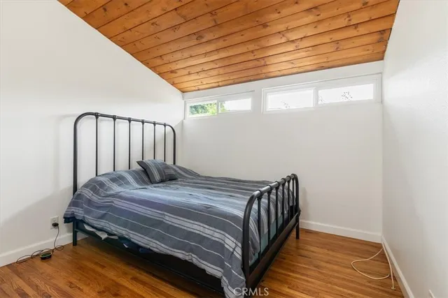 a bedroom with a bed a dresser and wooden floor
