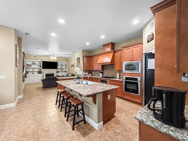 a large kitchen with stainless steel appliances granite countertop a stove refrigerator and a view of living room