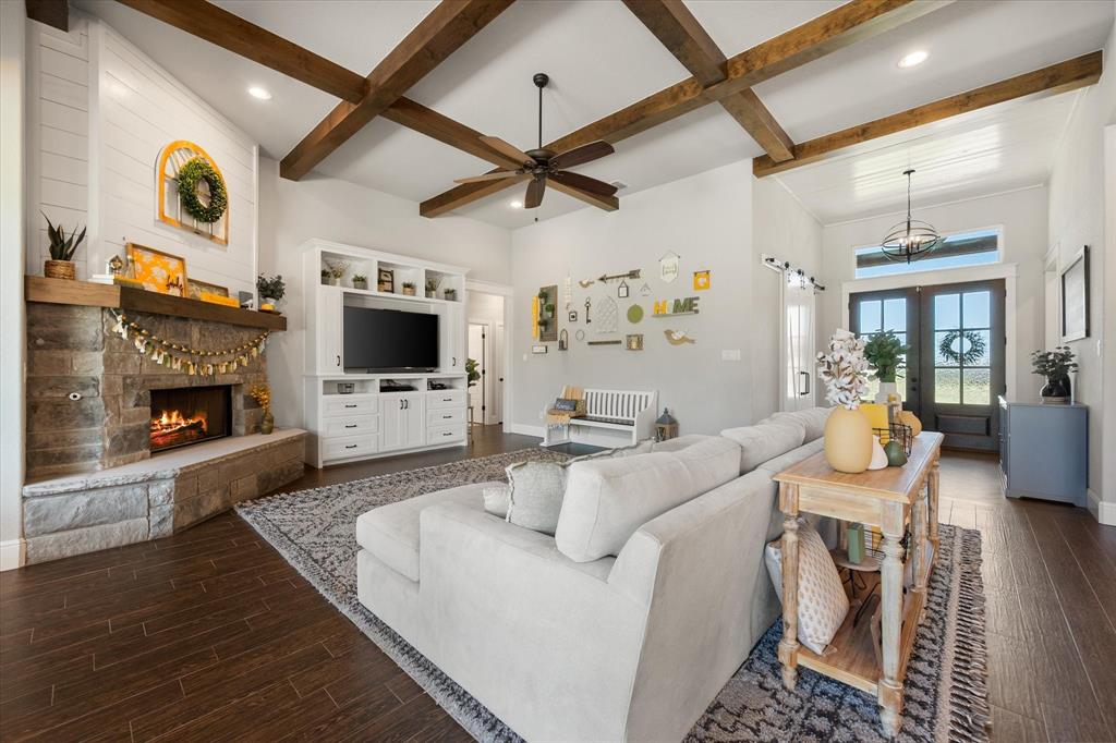 6425 Starlight Ranch Road Godley, TX 76044 - Photo 5 of 37 Wood beams crisscross the ceiling in this great room. The corner gas fireplace with wood mantle has stone below and shiplap to the ceiling.