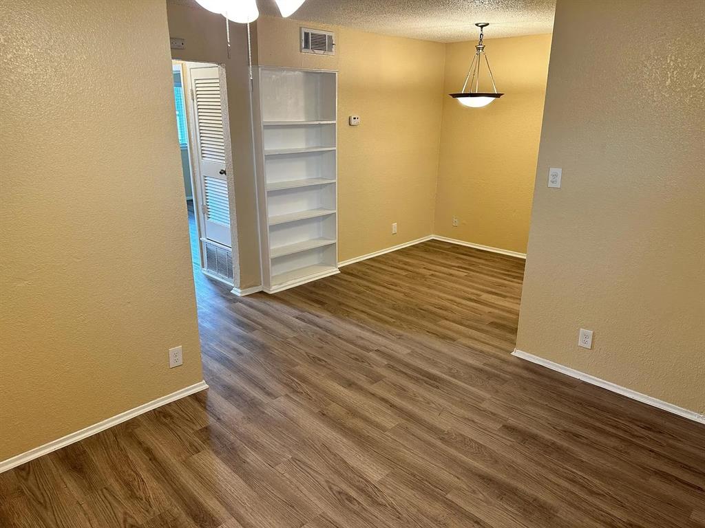 2401 Manor Road, Unit 220 Austin, TX 78722 - Photo 15 of 17 Warm wood-look flooring and built-in shelving anchor this versatile open-concept living space.