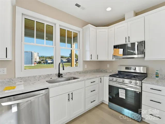 a kitchen with stainless steel appliances granite countertop a stove sink and cabinets