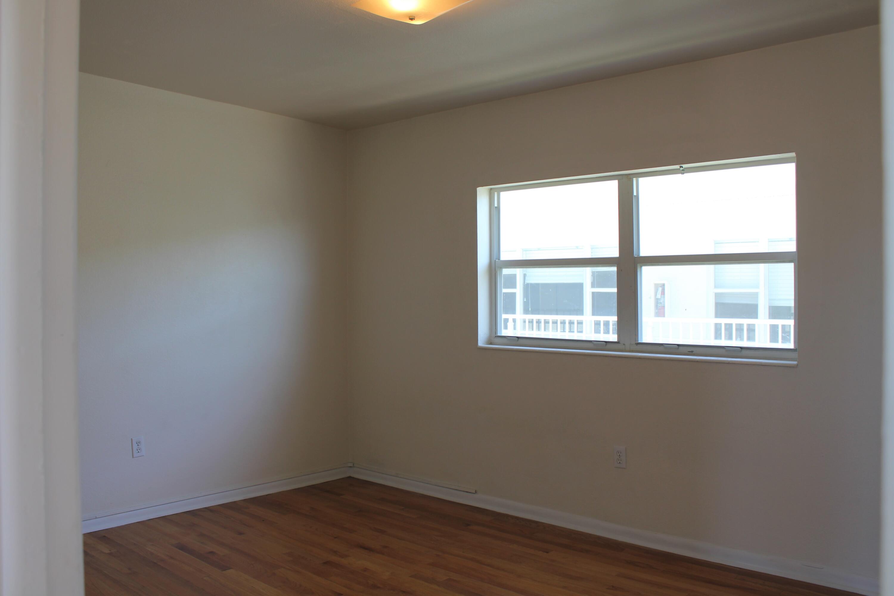 651 Palm Drive, Unit A4 Satellite Beach, FL 32937 - Photo 12 of 16 a view of an empty room with wooden floor and a window