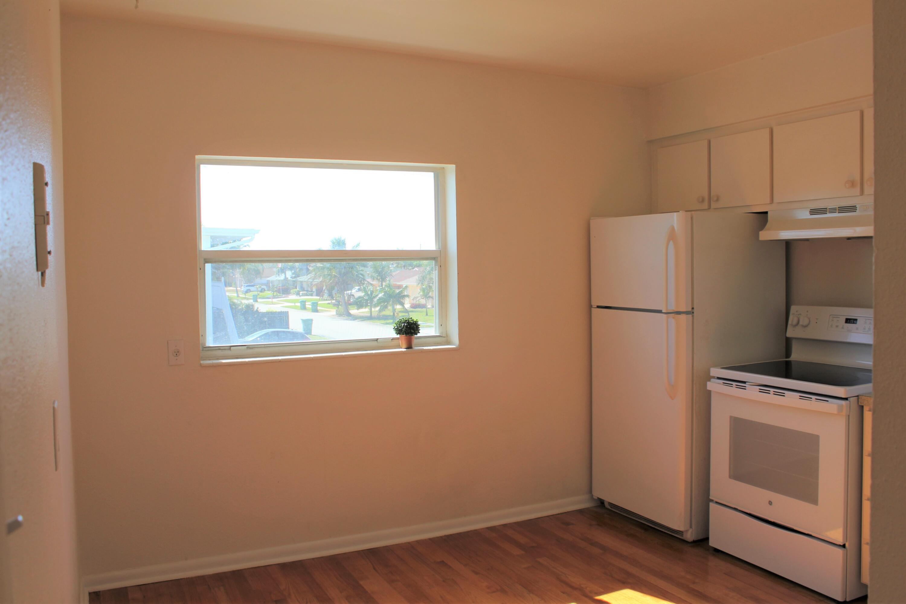 651 Palm Drive, Unit A4 Satellite Beach, FL 32937 - Photo 6 of 16 a kitchen with a refrigerator and white cabinets