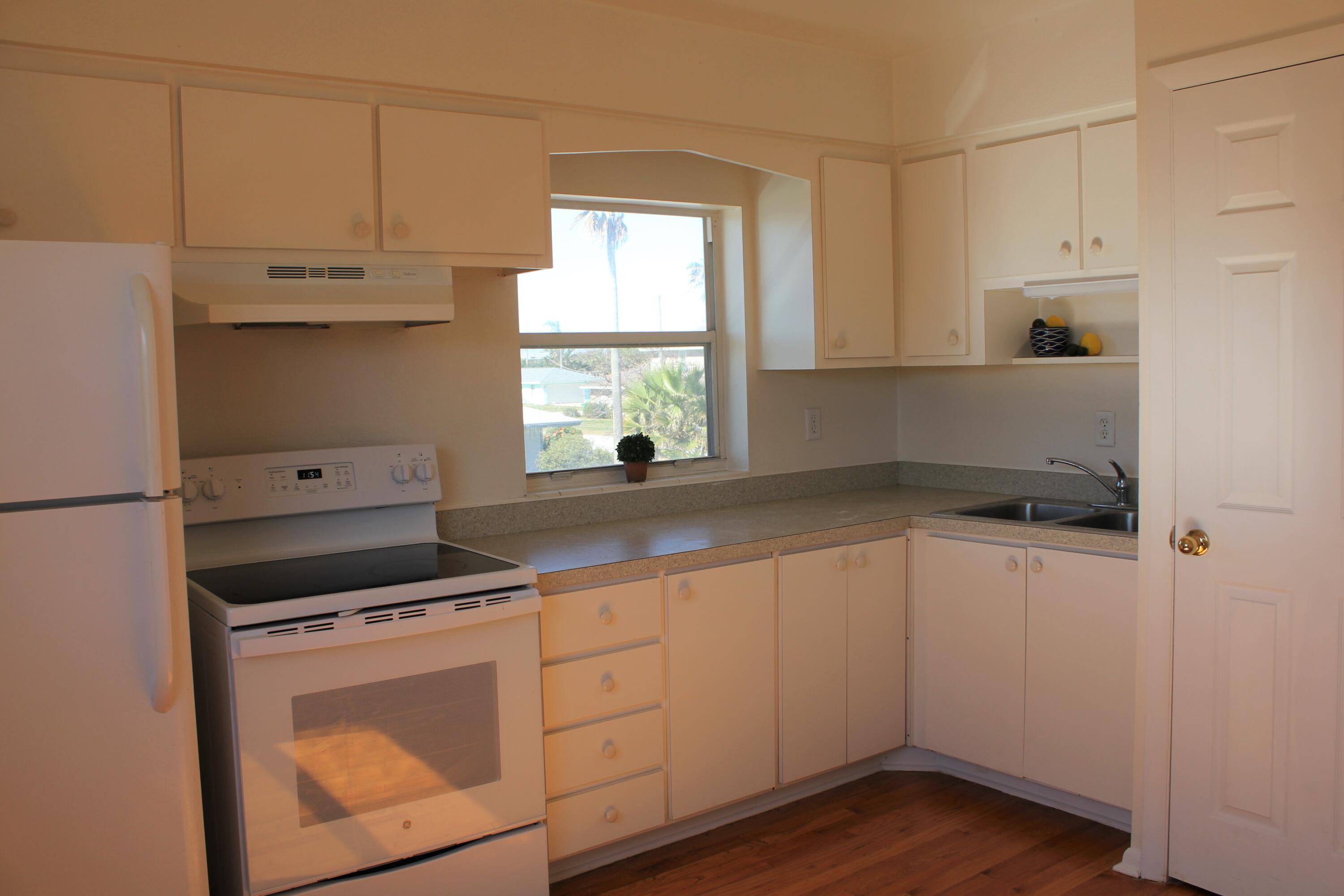 651 Palm Drive, Unit A4 Satellite Beach, FL 32937 - Photo 7 of 16 a kitchen with granite countertop white cabinets and white appliances