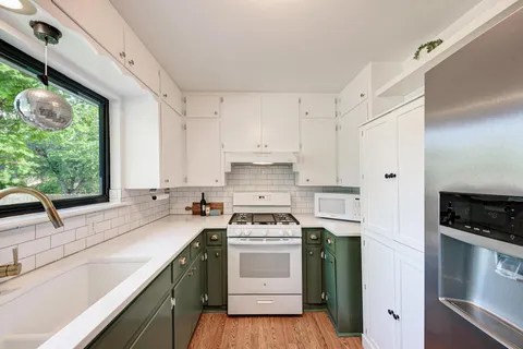a kitchen with stainless steel appliances white cabinets and a stove top oven