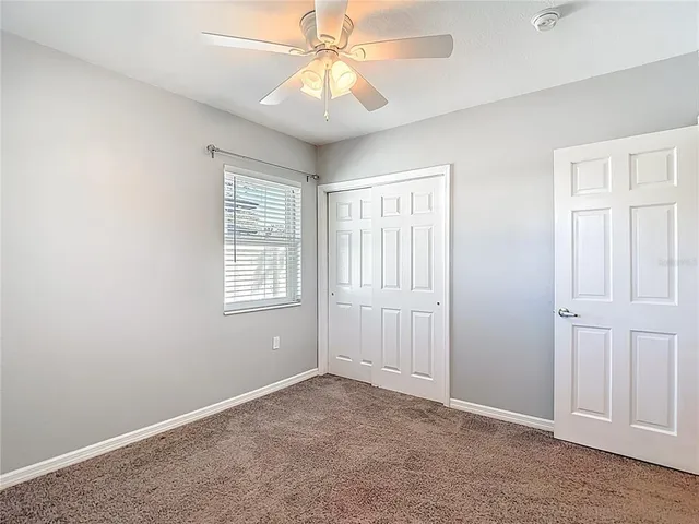 an empty room with windows and fan