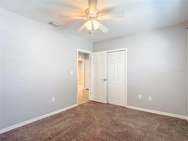 an empty room with a chandelier fan and windows