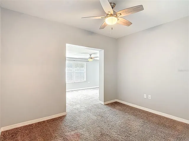 an empty room with a ceiling fan and a window