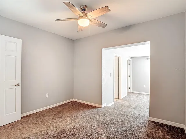 an empty room with a ceiling fan and a window
