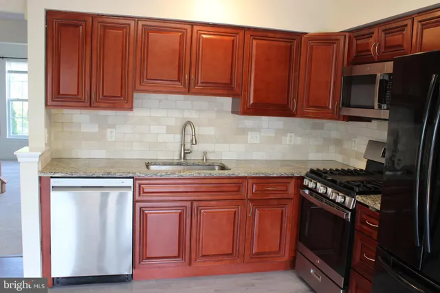 a kitchen with stainless steel appliances granite countertop a stove top oven a sink dishwasher and a microwave oven