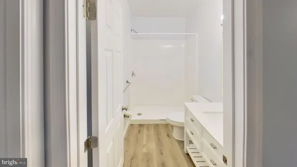 an empty room with wooden floor ceiling fan and windows