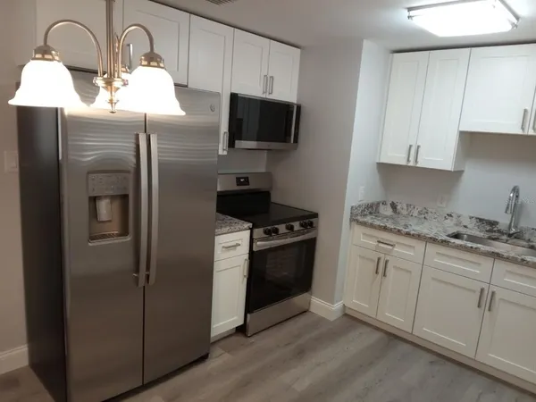 a kitchen with stainless steel appliances granite countertop a refrigerator and a stove top oven