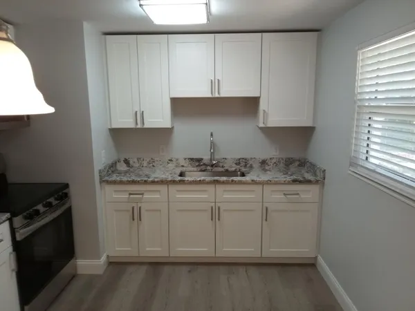 a kitchen with granite countertop white cabinets and a stove