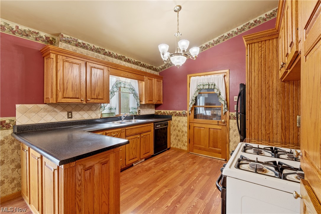 120 Lester Road New Franklin, OH 44319 - Photo 7 of 24 Kitchen featuring black appliances, a chandelier, brown cabinets, backsplash, and light hardwood floors