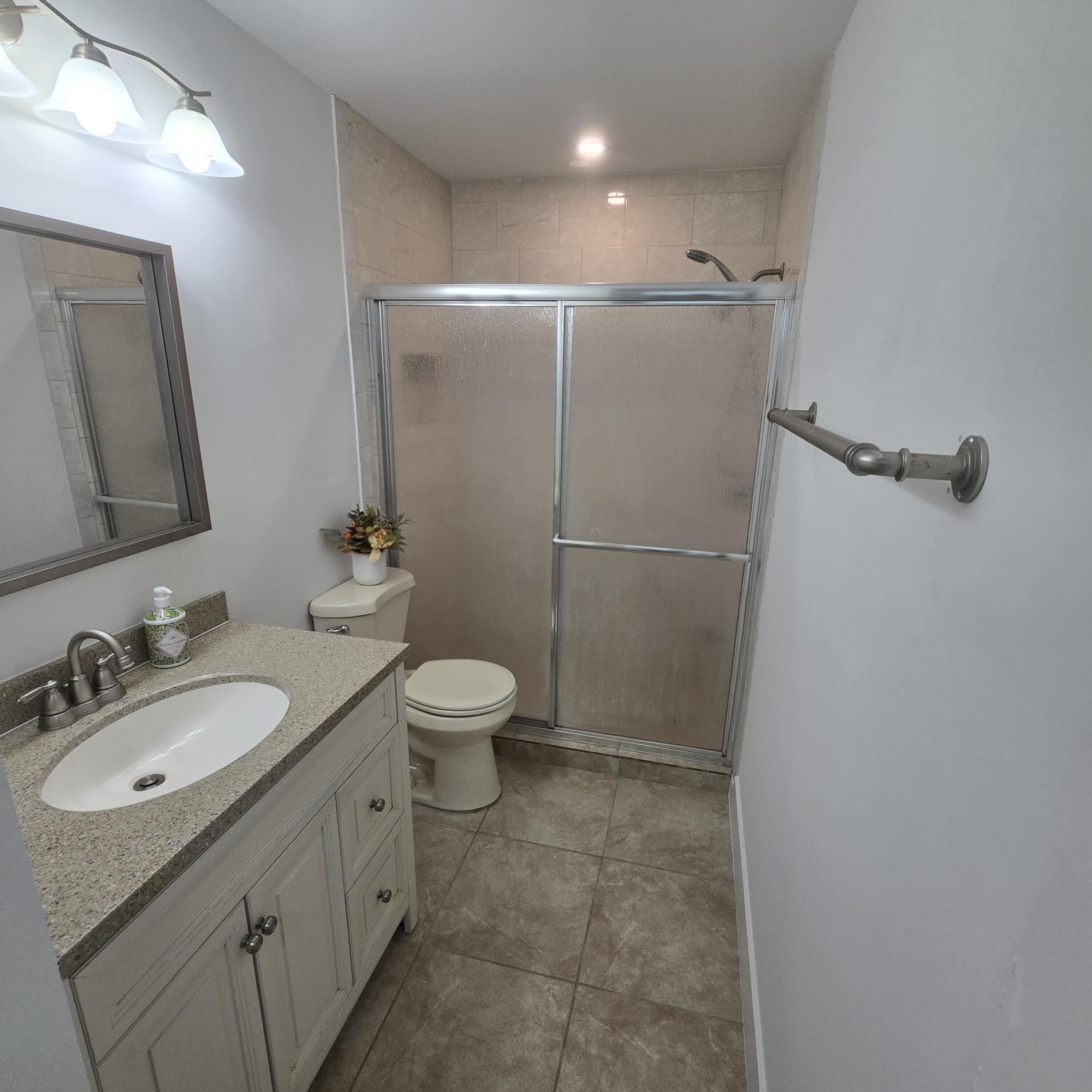 1237 Wynnedale Road, Unit 1237 West Palm Beach, FL 33417 - Photo 9 of 20 a bathroom with a granite countertop sink toilet and shower