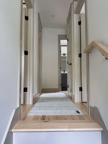 a view of a hallway with wooden floor and a cabinet