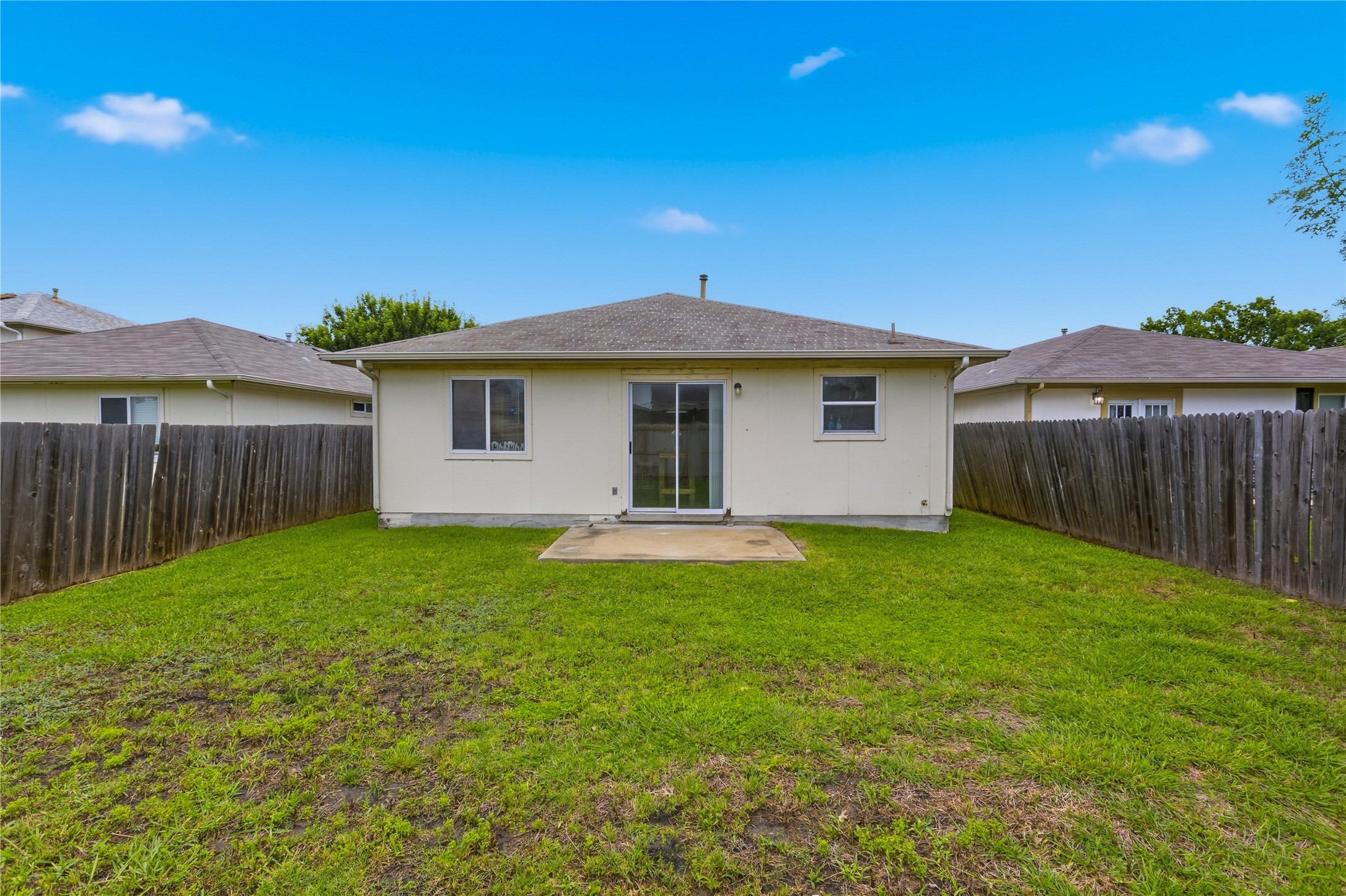 16112 Hamilton Point Circle Manor, TX 78653 - Photo 27 of 27 Expansive backyard featuring a concrete patio, sliding glass door access, two windows, and wood fencing