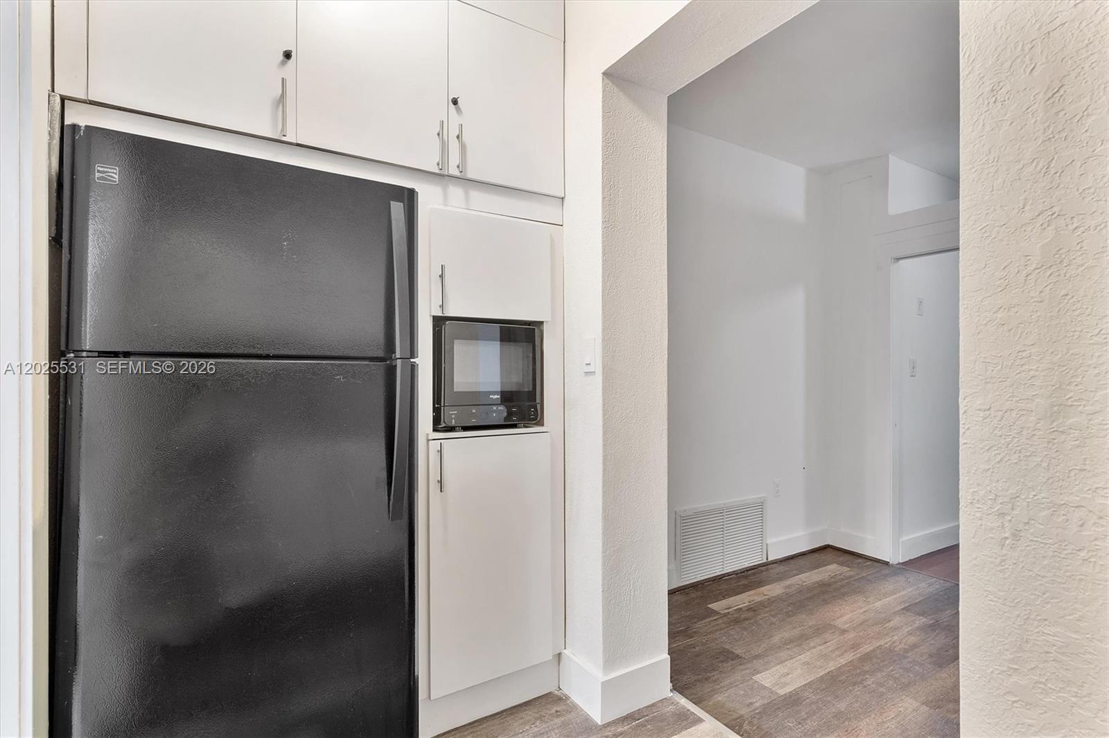 3951 Southwest 2nd Terrace, Unit 3951 Miami, FL 33134 - Photo 19 of 21 a view of a refrigerator in kitchen and an empty room with wooden floor