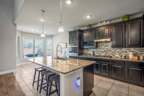a kitchen with stainless steel appliances granite countertop a kitchen island a stove and a sink