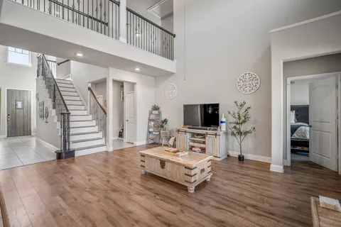 a living room with stainless steel appliances kitchen island a wooden floor and a view of kitchen