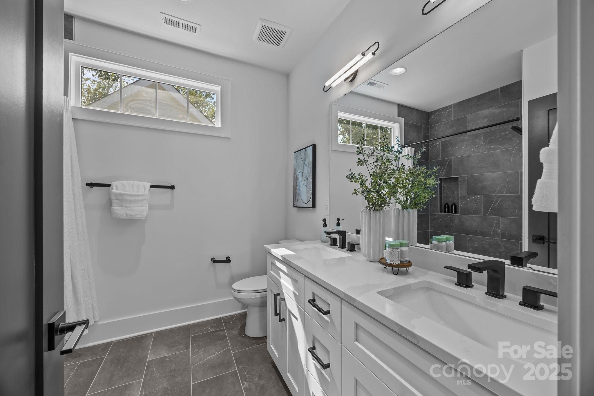 3945 Plainview Road Charlotte, NC 28208 - Photo 45 of 47 a bathroom with a double vanity sink a toilet and a mirror