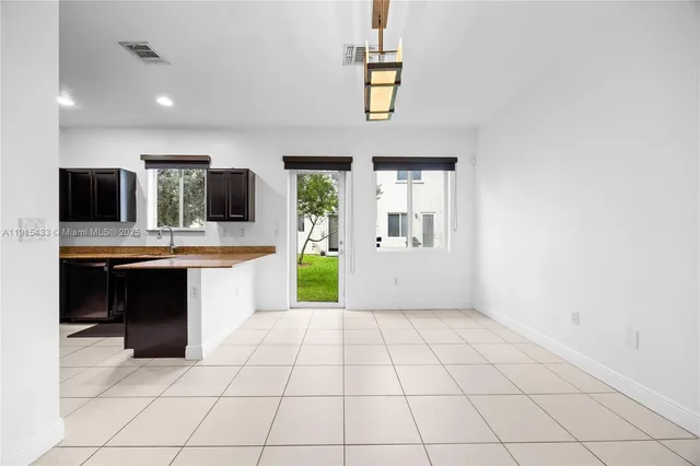 a large white kitchen with granite countertop a sink and dishwasher a stove top oven with wooden floor