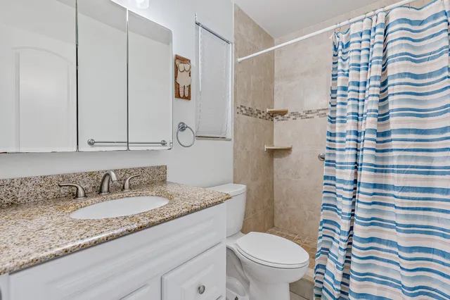 a bathroom with a granite countertop sink toilet and shower