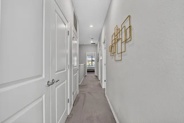 a view of a hallway with wooden floor and a bathroom