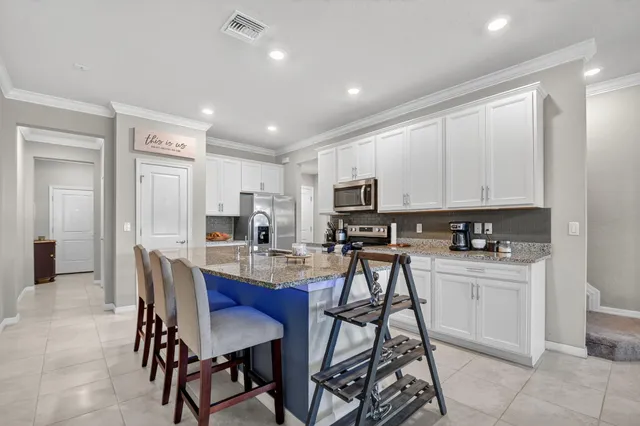a view of kitchen with cabinets stainless steel appliances dining table and chairs