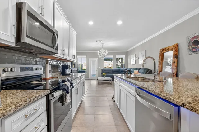 a kitchen with stainless steel appliances granite countertop a stove top oven a sink dishwasher a dining table and chairs with wooden floor