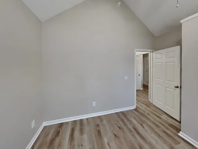 a view of an empty room with wooden floor and a bathroom