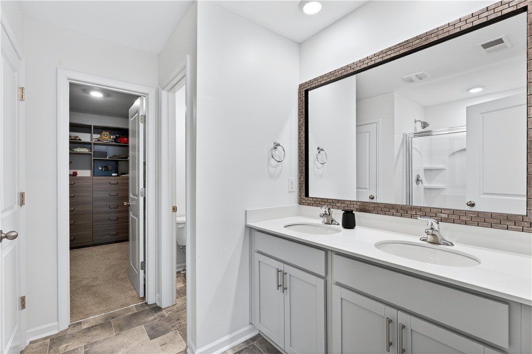 102 Preservation Drive Greer, SC 29650 - Photo 27 of 44 This modern primary bathroom features dual sinks and a large mirror, offering both style and convenience.