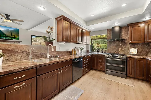 a kitchen with stainless steel appliances granite countertop wooden cabinets a stove top oven a sink and dishwasher