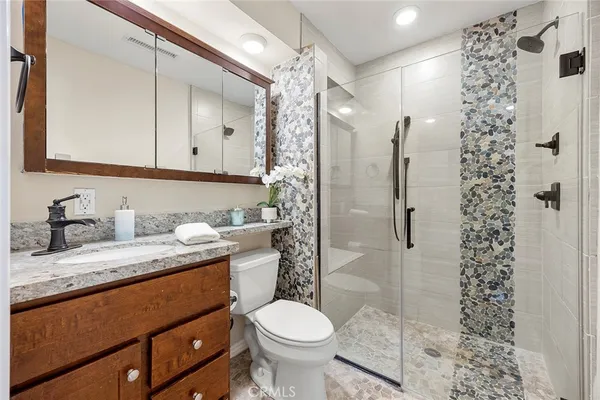 a bathroom with a granite countertop sink toilet and shower