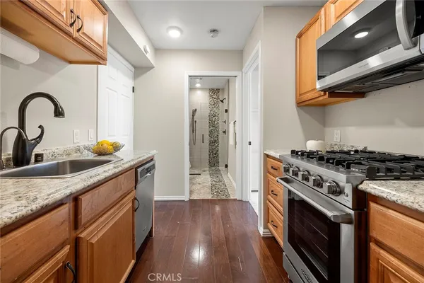 a kitchen with granite countertop a stove a sink and wooden floor
