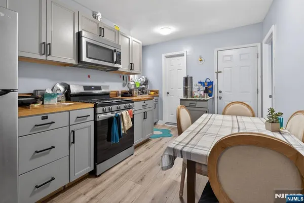 a kitchen with stainless steel appliances granite countertop a stove top oven a sink dishwasher and white cabinets with wooden floor