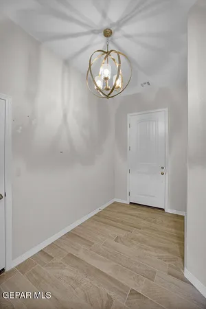 a view of an empty room with a chandelier fan