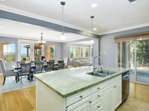 a view of center island of a kitchen with granite countertop living room a refrigerator and couches