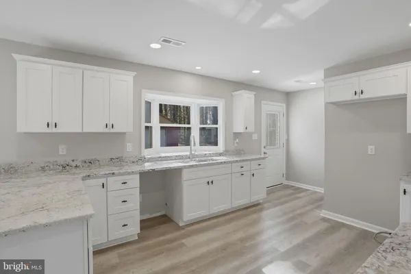 a kitchen with granite countertop white cabinets and sink